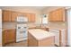 A well-lit kitchen with light wood cabinetry, an island and tile flooring at 10422 Stokeshill Ct, Pineville, NC 28134
