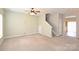An open living room with beige carpet, ceiling fan and a staircase leading to the second floor at 10422 Stokeshill Ct, Pineville, NC 28134