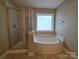Bathroom showcasing a soaking tub with a window and a separate glass-enclosed shower at 10927 Kinnairds St, Charlotte, NC 28278
