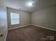 A carpeted bedroom with a single window and neutral paint at 10927 Kinnairds St, Charlotte, NC 28278