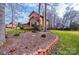 Side view of a tan home with a red roof, surrounded by greenery and mulch beds at 1228 Hidden Creek Cir, Hickory, NC 28602