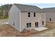 Two-story home featuring tan siding, a concrete patio, and glass patio doors to the backyard at 124 Rustling Waters Dr, Mooresville, NC 28117