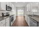 Modern kitchen features stainless steel appliances, granite countertops, white cabinetry, and wood-look floors at 136 S Bell Ave, Albemarle, NC 28001