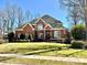 Charming two-story brick home with manicured lawn and mature trees on a sunny day at 19622 River Falls Dr, Davidson, NC 28036