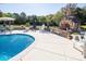 Backyard swimming pool area with a stone fireplace, lounge chairs, and manicured landscaping, ideal for outdoor relaxation at 3099 Trinity Church Rd, Concord, NC 28027
