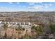Aerial view of a neighborhood showcases a community surrounded by lush greenery and tree coverage under a bright blue sky at 3212 Burnello Ct, Iron Station, NC 28080