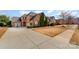 View of a brick two-story home featuring an expansive driveway, well-manicured lawn and mature landscaping at 333 Willow Brook Dr, Matthews, NC 28105