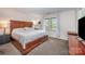 A bedroom with a dark wood bedframe and matching bedside tables, with lots of natural light streaming in at 3400 Thistle Bloom Ct, Charlotte, NC 28269