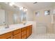 Bright primary bathroom featuring a double sink vanity with wood cabinets, a soaking tub, and tile flooring at 3612 Brookstone Trl, Indian Trail, NC 28079