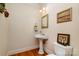 Charming powder room with pedestal sink, wood floors, and decorative artwork at 4828 Beth Ln, Harrisburg, NC 28075