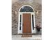 Close-up of front door framed by brick, sidelights, and a transom window, enhanced with sconces and a potted plant at 7306 Timbercreek Ct, Denver, NC 28037