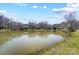 Peaceful water view of a serene pond bordered by trees, with residential homes in the distance at 7306 Timbercreek Ct, Denver, NC 28037