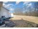 Wide shot of a grassy backyard with trees in the background, adjacent to a house with a white door and two bicycles at 10530 Stoneacre Ct, Pineville, NC 28134