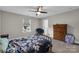 Bright bedroom features a ceiling fan, plush carpet and a floral comforter, next to a dark wood dresser at 122 Round Rock Rd, Troutman, NC 28166