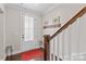 Bright foyer entrance featuring a red rug, decorative hooks, and a staircase with a white banister at 135 Goldenrod Cir, Salisbury, NC 28147