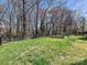 View of the backyard with lush green grass, garden area, and surrounding bare trees at 1394 Fitzgerald Nw St, Concord, NC 28027