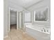 Bright bathroom featuring a soaking tub, glass enclosed shower, and neutral tile floors at 1394 Fitzgerald Nw St, Concord, NC 28027