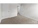 A bright bedroom with neutral carpet, white walls and a doorway to another room at 142 S Bell Ave, Albemarle, NC 28001