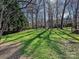 Well-manicured backyard with lush green grass, mature trees, and partial fence, perfect for outdoor enjoyment at 15715 Holyhead Ln, Huntersville, NC 28078