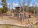 Multi-level waterfront home featuring stairs and decks leading to the lake, surrounded by mature trees and natural landscaping at 18607 Mainsail Ct, Lancaster, SC 29720