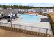 Community pool area featuring a large, modern pool with umbrellas and seating, surrounded by a black fence at 18607 Mainsail Ct, Lancaster, SC 29720