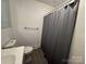 Compact bathroom featuring a toilet, sink, shower with gray textured curtain and gray vinyl flooring at 216 W Shannonhouse St, Shelby, NC 28152
