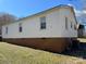 Side exterior of home with neutral siding and visible foundation, set against a clear blue sky at 216 W Shannonhouse St, Shelby, NC 28152