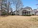 A sprawling backyard features a screened porch, a neat lawn, mature trees, and a rustic fire pit at 2300 Bonnie Butler Way, Charlotte, NC 28270
