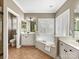 Bright bathroom featuring double sinks, tile flooring, and a soaking tub under a window with white shutters at 2300 Bonnie Butler Way, Charlotte, NC 28270