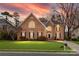 Charming brick home features manicured lawn and dark shutters at dusk at 2300 Bonnie Butler Way, Charlotte, NC 28270