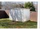 Backyard view of outdoor storage shed with double doors, surrounded by green grass and a wooden privacy fence at 2359 Eagle Glen Ct, Gastonia, NC 28056