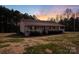 A charming home at dusk, featuring a welcoming porch and set on a large, well-maintained lawn at 24654 Helms Rd, Albemarle, NC 28001