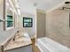 Bathroom featuring dual sinks, granite countertops, tiled tub, and a black framed window at 414 N Wylie St, Lancaster, SC 29720