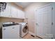 Functional laundry room featuring white cabinets, a tiled floor, and modern front-load washer and dryer units at 4763 River Hills Dr, Denver, NC 28037