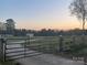 Property gate, with a gravel drive, set against a colorful twilight sky at 485 Harper Miller Dr, Cleveland, NC 27013