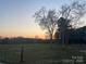 Beautiful view of a large open grass-filled field lined by trees under a colorful sky at 485 Harper Miller Dr, Cleveland, NC 27013