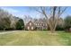 Sprawling two-story brick home boasting a lush green lawn, mature trees, and a welcoming covered front porch at 518 Streamside Ln, Marvin, NC 28173