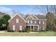 Imposing two-story brick home featuring symmetrical design, black shutters, mature landscaping and covered entryway at 518 Streamside Ln, Marvin, NC 28173