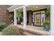 Charming covered front porch adorned with hanging plants, neutral furniture, and an elegant front door with glass panels at 518 Streamside Ln, Marvin, NC 28173