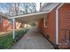 Side view of brick home with covered walkway and manicured landscaping at 5435 Farmbrook Dr, Charlotte, NC 28210