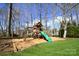Wooden playground featuring a slide and swings, perfect for outdoor activities in a landscaped backyard at 6016 Dogwood Blvd, Kannapolis, NC 28081