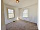 A bright bedroom featuring two windows and neutral carpet at 826 E Alexander St, Lincolnton, NC 28092