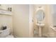 Bright powder room featuring pedestal sink and a decorative oval mirror with light fixture at 9018 Seamill Rd, Charlotte, NC 28278