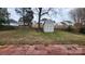 Spacious backyard with green grass, a brick patio, mature trees, and a storage shed at 10607 Old Bridge Ln, Charlotte, NC 28269