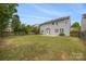 Expansive backyard showcasing a well-maintained lawn, mature trees, and a home with a patio at 10933 Sedgemoor E Ln, Charlotte, NC 28277