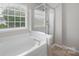Bright bathroom featuring soaking tub and glass-enclosed shower at 10933 Sedgemoor E Ln, Charlotte, NC 28277