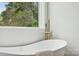 Bright bathroom featuring a soaking tub, gold fixtures, and a window with nature views for ultimate relaxation at 1210 Skyview Rd, Charlotte, NC 28208
