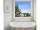 Bright bathroom featuring a soaking tub, gold fixtures, artwork, and a window view for ultimate relaxation at 1210 Skyview Rd, Charlotte, NC 28208