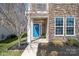 Inviting entrance with a bright blue door, stone accents, and manicured landscaping at 13925 Helen Benson Blvd, Davidson, NC 28036