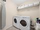 A clean and functional laundry room equipped with a washer, dryer, and storage shelves at 13925 Helen Benson Blvd, Davidson, NC 28036